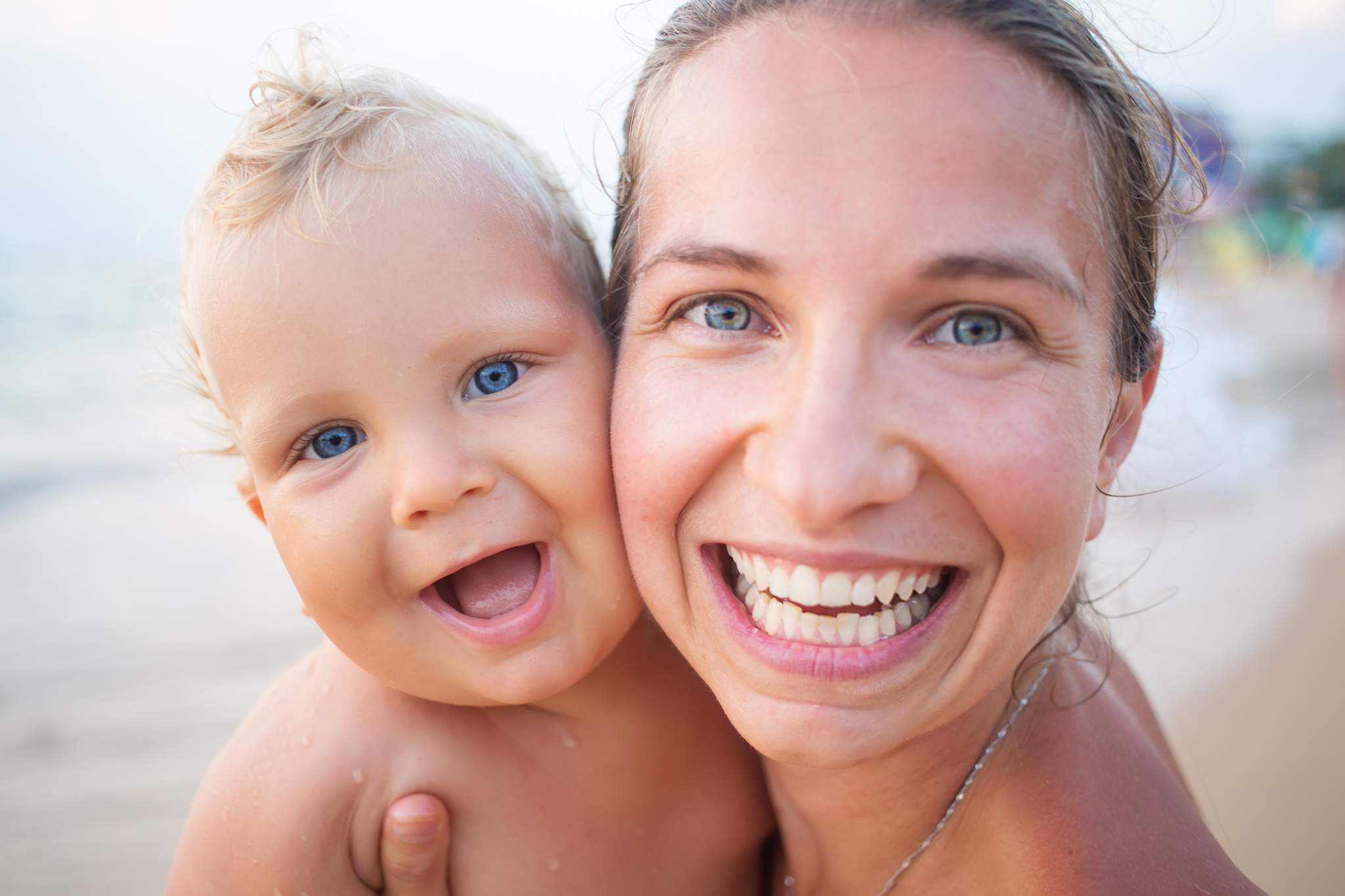A mother and her baby are smiling at camera